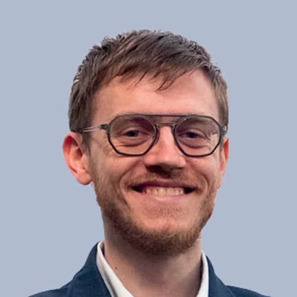 Homme souriant portant des lunettes, portrait professionnel pour OPTIMA.ai.