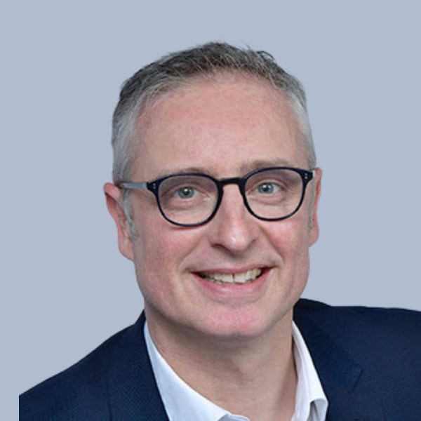 Homme souriant en costume avec lunettes, portrait professionnel.