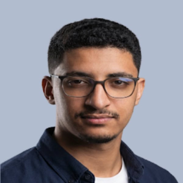 Jeune homme portant des lunettes et chemise bleue, portrait professionnel.